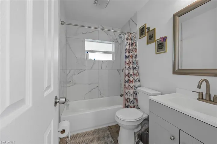 Bathroom featuring vanity and shower / bathtub combination with curtain