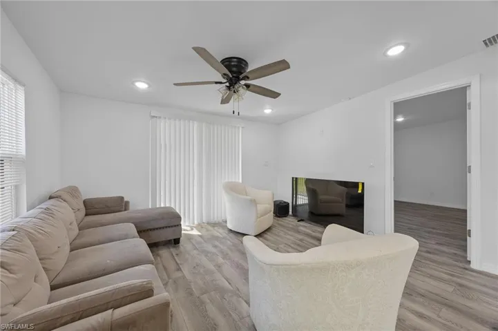 Living area with light wood-style flooring, ceiling fan, recessed lighting, and plenty of natural light