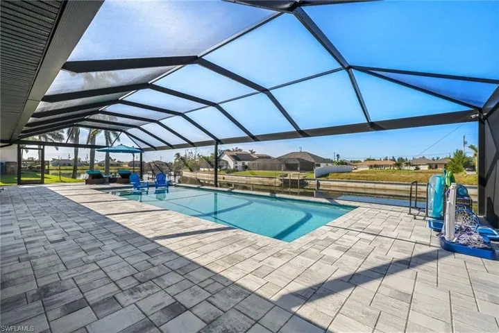 View of pool with glass enclosure and a patio