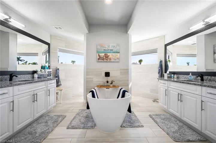 Bathroom with tile patterned floors, vanity, a bath, and tile walls