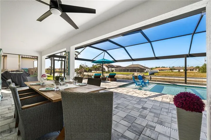 View of swimming pool with ceiling fan, a patio area, and glass enclosure