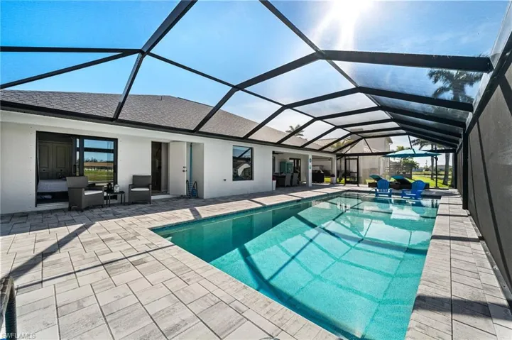 View of swimming pool featuring glass enclosure and a patio