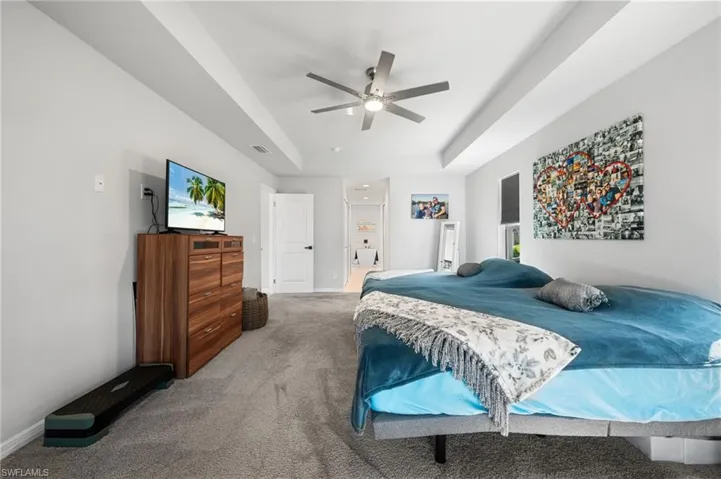Carpeted bedroom with ceiling fan and a raised ceiling