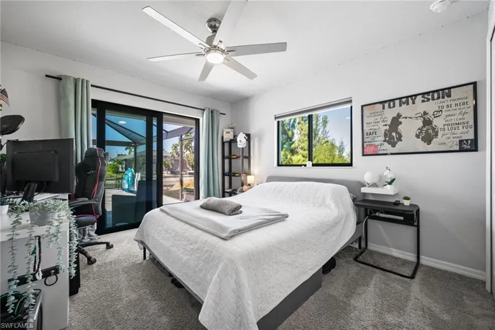 Carpeted bedroom featuring access to exterior, ceiling fan, and multiple windows