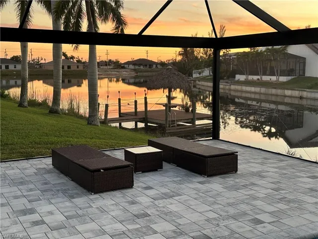 Patio terrace at dusk featuring a lawn and a water view