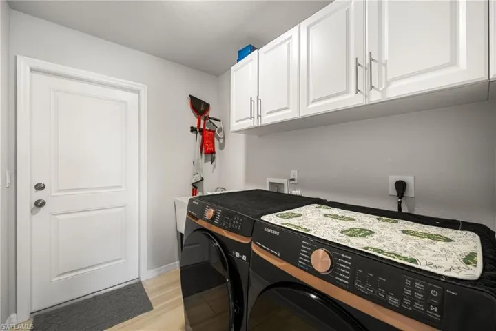 Laundry room featuring cabinets, light wood-type flooring, and washer and clothes dryer