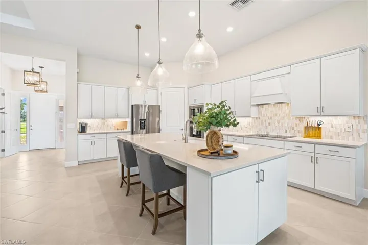 Kitchen featuring decorative backsplash, stainless steel fridge with ice dispenser, pendant lighting, a spacious island, and recessed lighting
