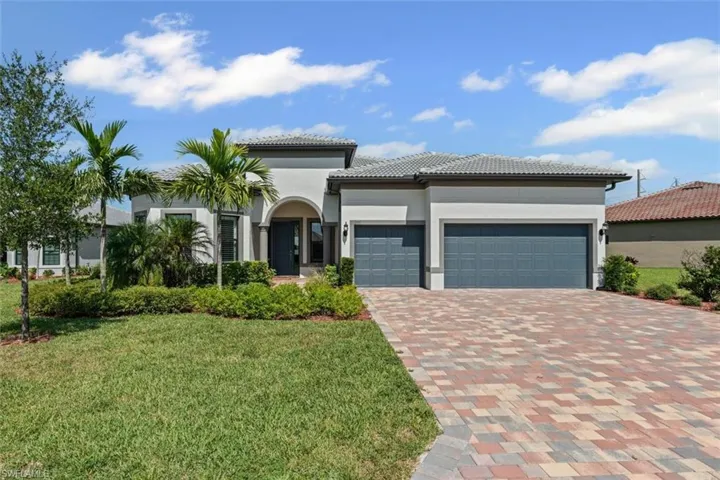 Mediterranean / spanish-style house with an attached garage, driveway, a front lawn, stucco siding, and a tile roof