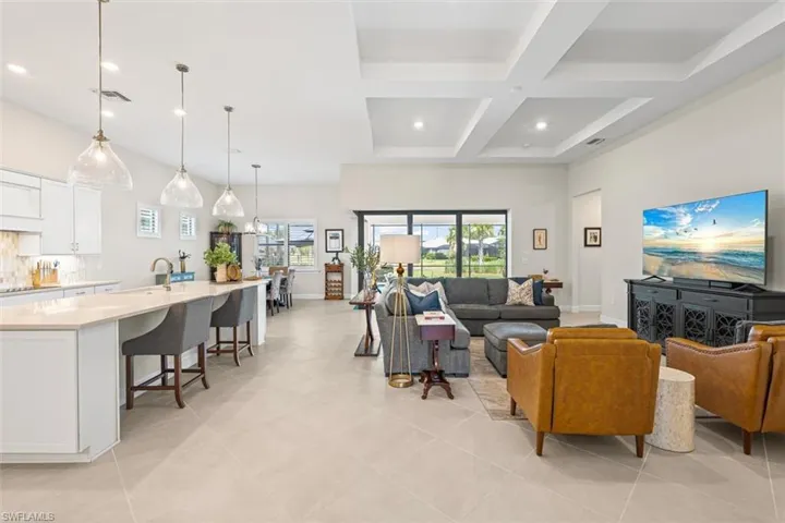 Living area with coffered ceiling, recessed lighting, beam ceiling, light tile patterned flooring, and a chandelier