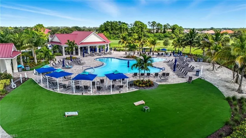 Community pool with a patio, view of scattered trees, and a lawn