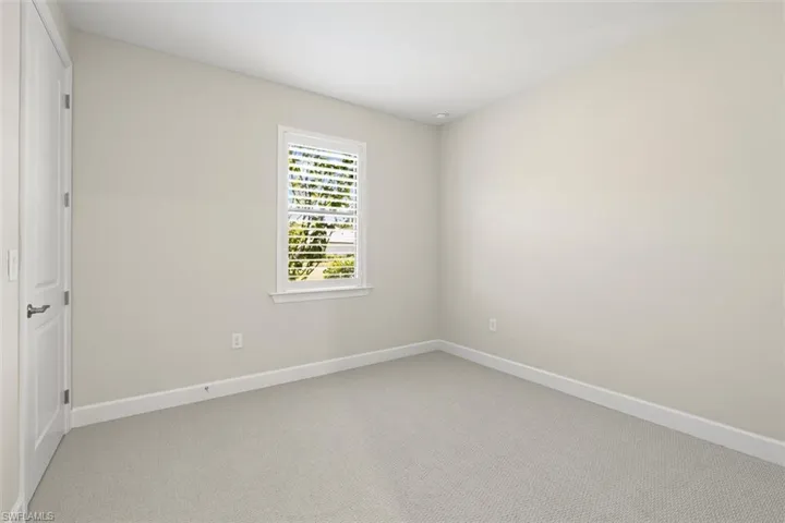 Unfurnished room featuring light carpet and baseboards