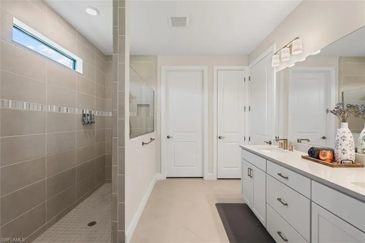 Bathroom with walk in shower, double vanity, and tile patterned floors