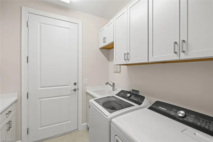 Washroom featuring washing machine and dryer, cabinet space, and light tile patterned floors