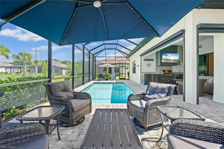 Swimming pool featuring exterior kitchen, a lanai, an outdoor hangout area, and a patio area