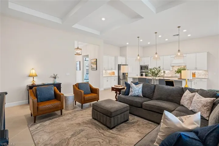Living room featuring recessed lighting, light tile patterned flooring, beamed ceiling, and coffered ceiling