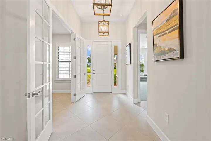 Foyer entrance featuring plenty of natural light, light tile patterned floors, a chandelier, and french doors
