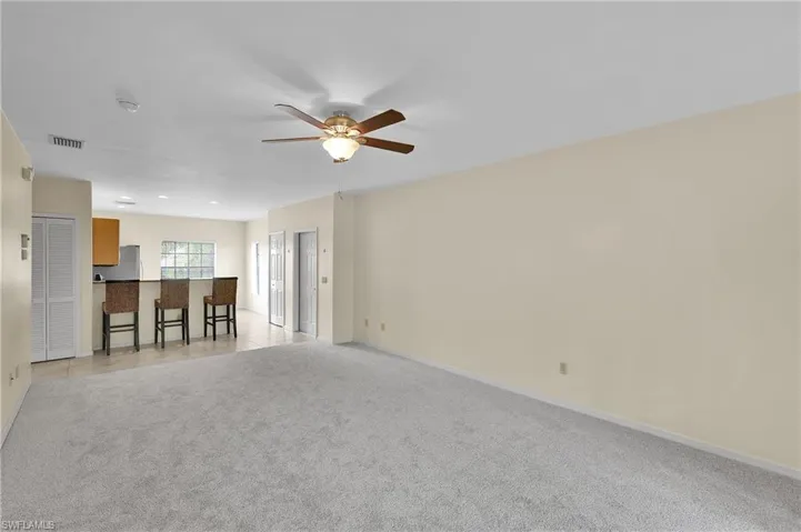Unfurnished living room featuring light carpet and ceiling fan