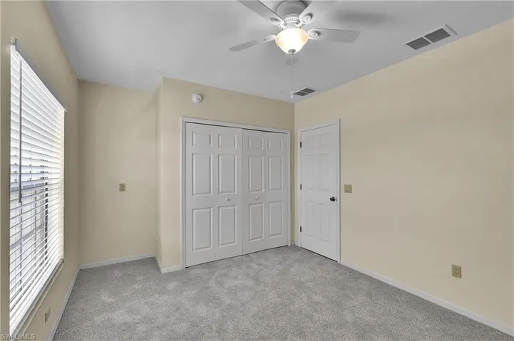 Unfurnished bedroom with light carpet, a closet, and a ceiling fan