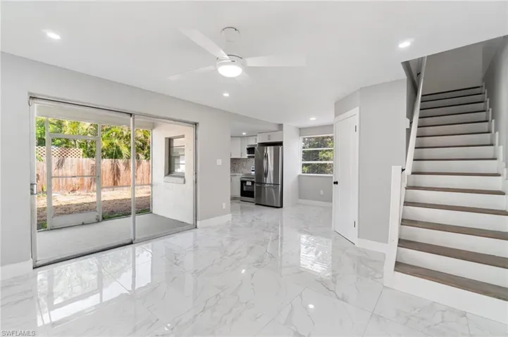 Unfurnished living room featuring baseboards, a ceiling fan, light marble finish flooring, stairway, and recessed lighting