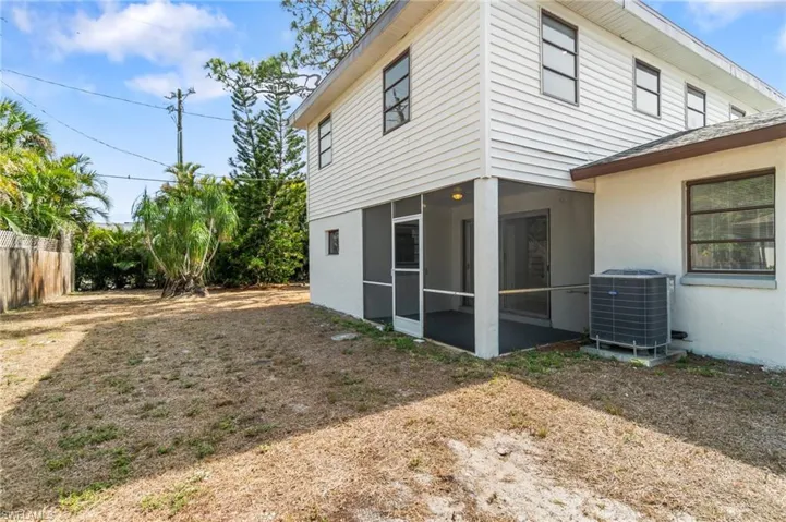 Back of house featuring central AC, a sunroom, stucco siding, and fence