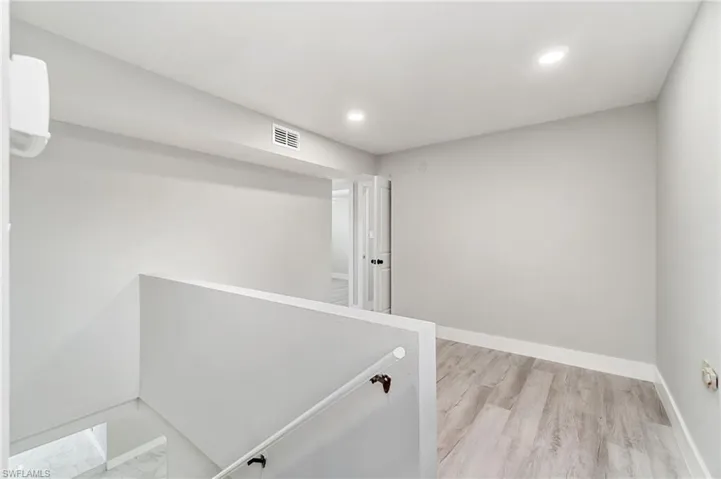Hallway featuring recessed lighting, baseboards, and an upstairs landing