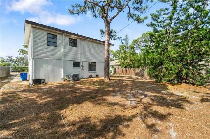 Rear view of property with fence and central AC