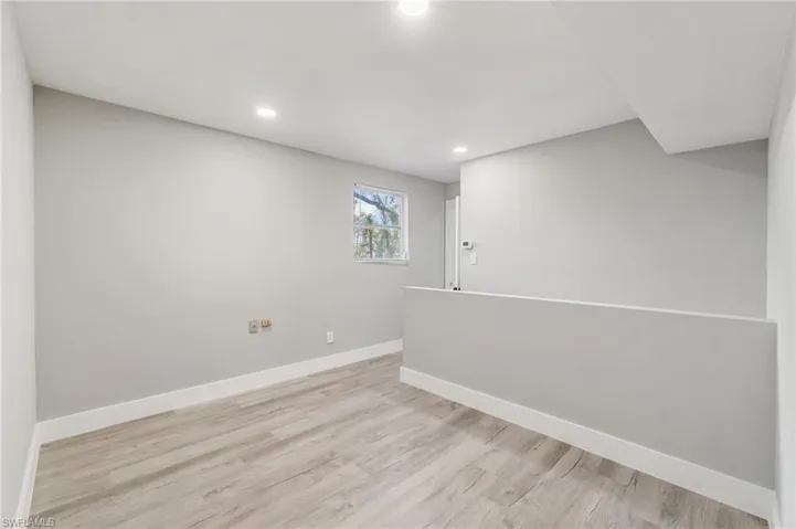 Basement featuring baseboards, light wood-style flooring, and recessed lighting