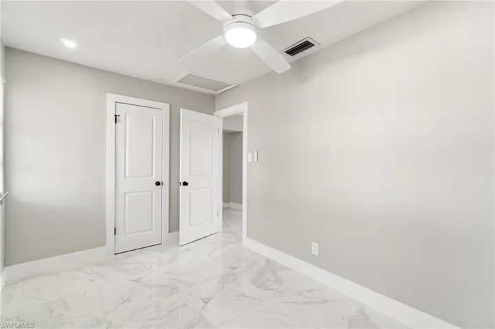 Unfurnished bedroom with light marble finish floors, attic access, baseboards, a ceiling fan, and recessed lighting