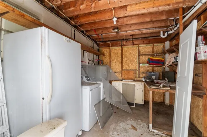 Unfinished basement with freestanding refrigerator and washer and clothes dryer