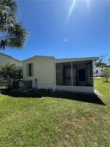 Rear view of house with a yard, central AC unit, and a sunroom