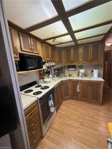 Kitchen with stove, light wood-style flooring, brown cabinetry, and light countertops