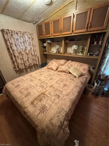 Bedroom with dark wood-style floors and vaulted ceiling