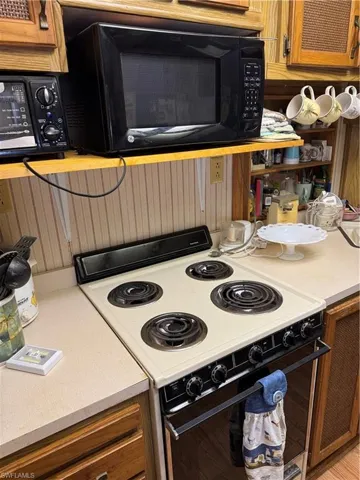 Kitchen with brown cabinetry, white electric range oven, and light countertops