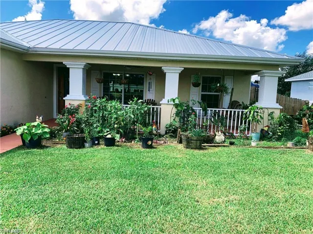 Back of property with stucco siding, a lawn, a standing seam roof, and a metal roof
