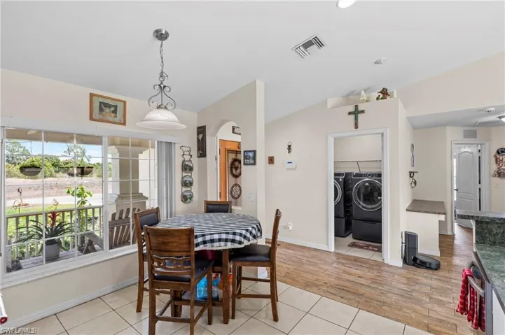 Dining room with light tile patterned flooring, washer and dryer, and arched walkways