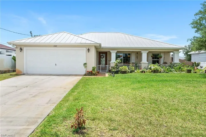 View of front of house featuring a porch, stucco siding, driveway, and a front lawn