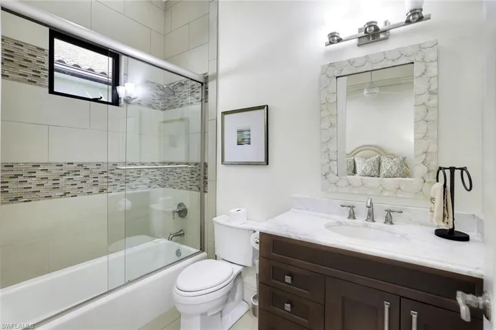 Bathroom with vanity and bath / shower combo with glass door