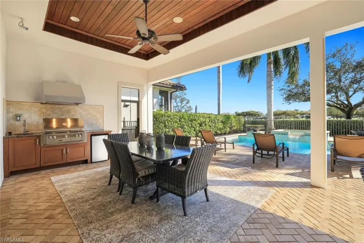 View of patio with an outdoor kitchen / dining area, ceiling fan, and a pool with connected hot tub