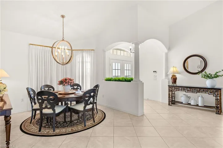 Dining space with a chandelier, ornate columns, light tile patterned floors, a high ceiling, and arched walkways
