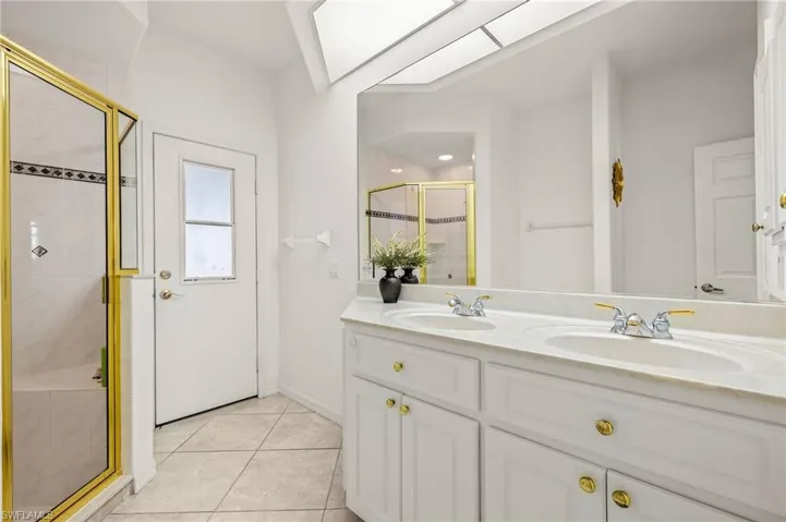 Full bath with a stall shower, double vanity, and tile patterned floors