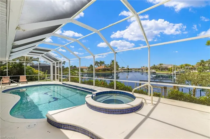 View of pool with a water view, a patio area, a lanai, and a pool with connected hot tub