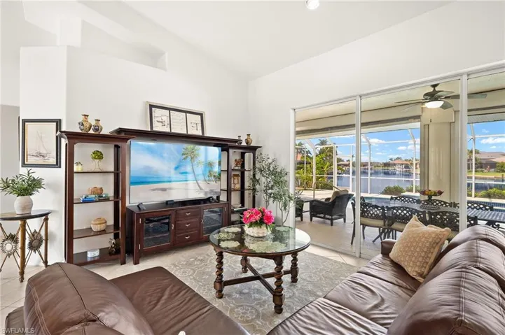 Living room featuring vaulted ceiling, tile patterned flooring, and a ceiling fan