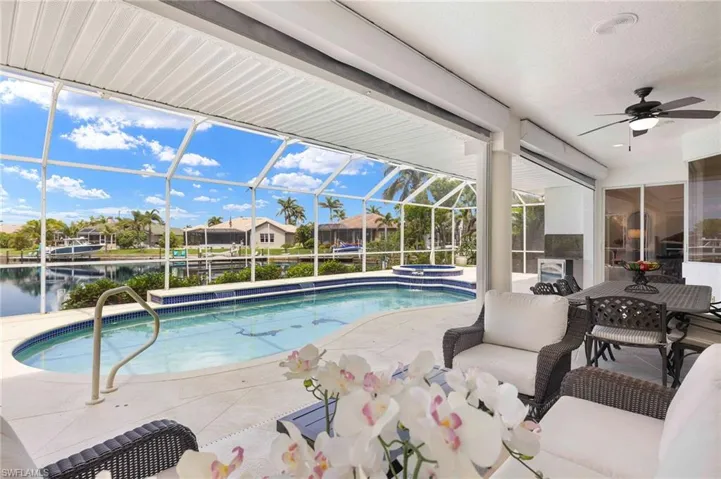 View of pool with a ceiling fan, a patio, a pool with connected hot tub, a water view, and glass enclosure