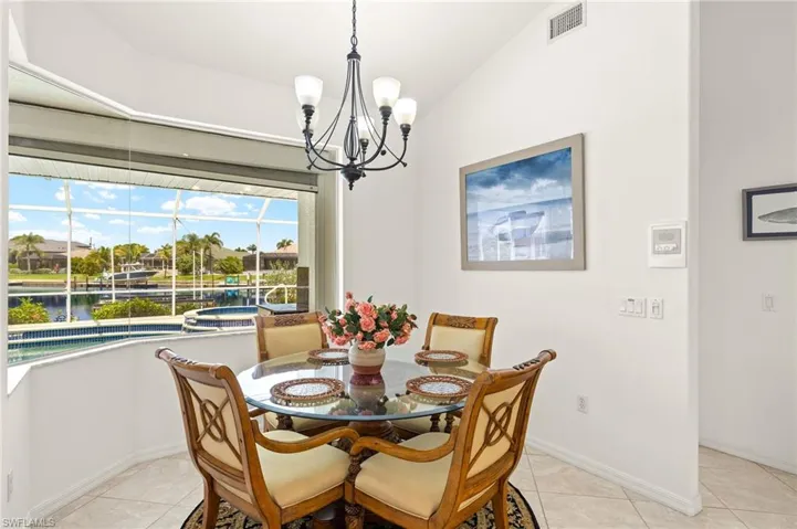 Dining area with a chandelier, light tile patterned floors, and a water view
