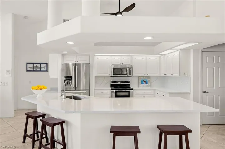 Kitchen with stainless steel appliances, light tile patterned flooring, a breakfast bar, decorative backsplash, and recessed lighting