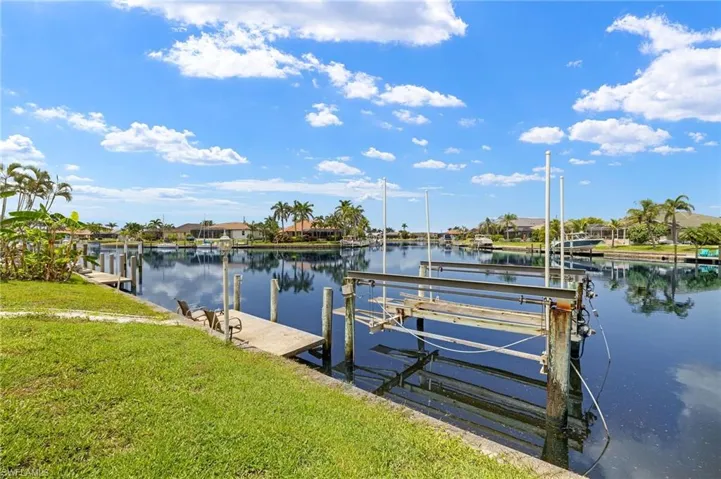 Dock with a water view, boat lift, and a yard