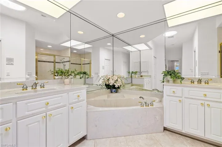 Bathroom featuring a garden tub, a shower stall, two vanities, recessed lighting, and tile patterned floors