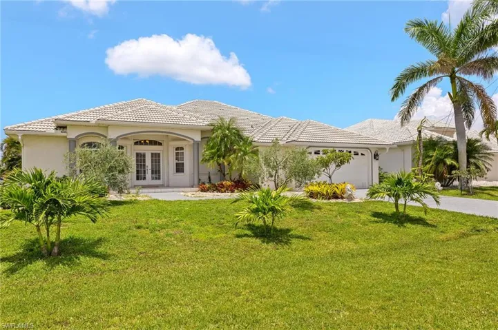 View of front of house with french doors, an attached garage, a front yard, a tile roof, and stucco siding