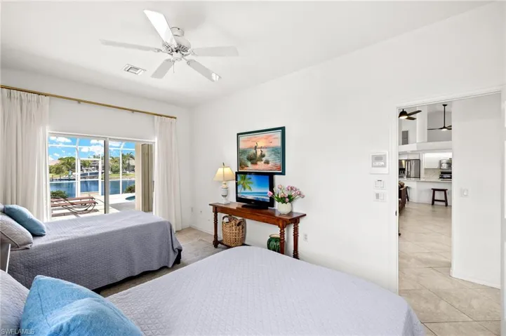 Bedroom with access to outside, light tile patterned flooring, ceiling fan, and stainless steel fridge