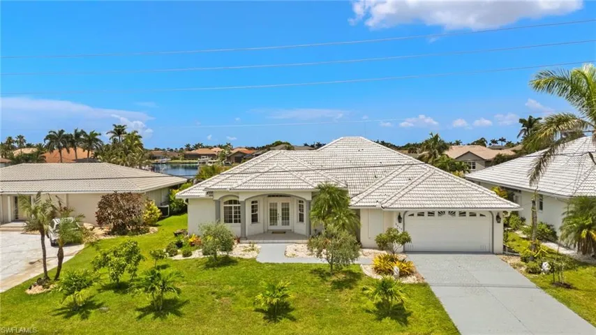 View of front of house with french doors, a tiled roof, an attached garage, a front yard, and stucco siding
